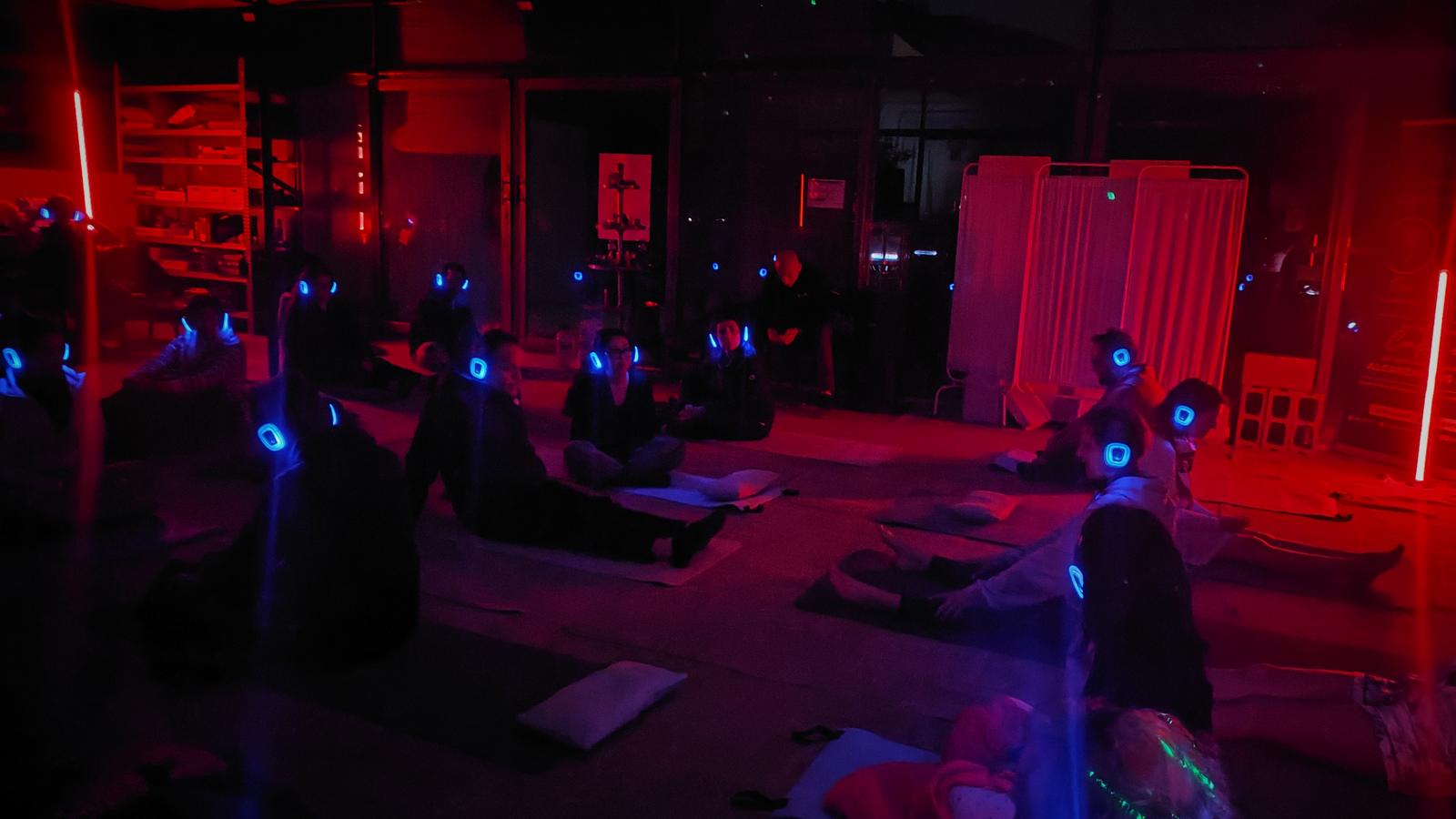 Participantes con auriculares iluminados en una sala en penumbra roja