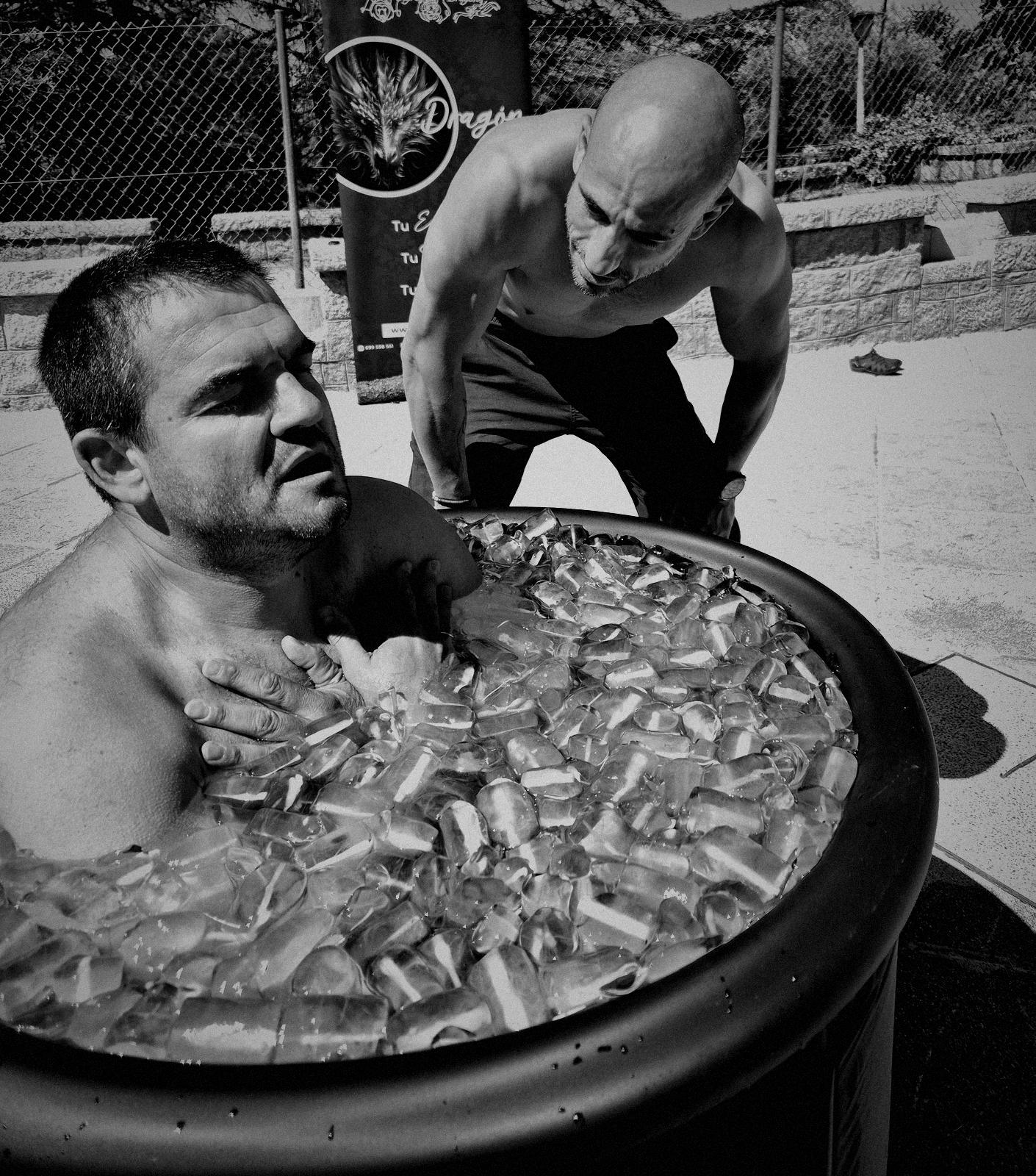 Un participante respira dentro de una bañera de hielo mientras el facilitador lo guía